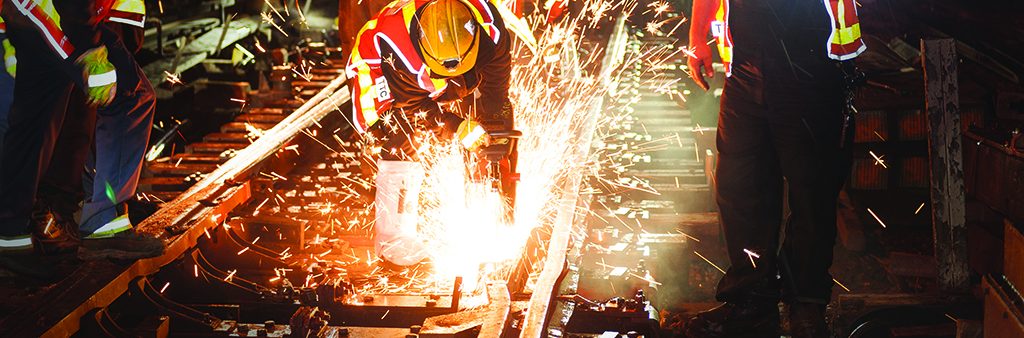 Welders working on a subway track underground.