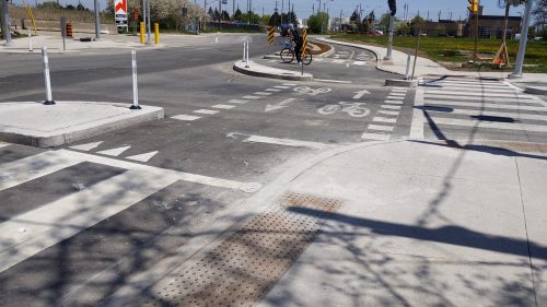 A person on a bike waits behind a corner island at a protected intersection.