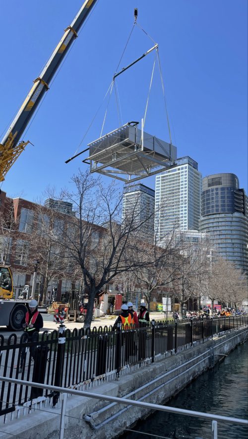 A crane moving a piece of metal at the Waterfront Building alongside the Toronto Harbourfront.
