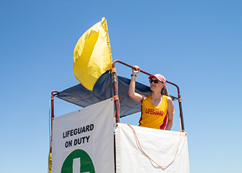 A lifeguard stand with a yellow flag.