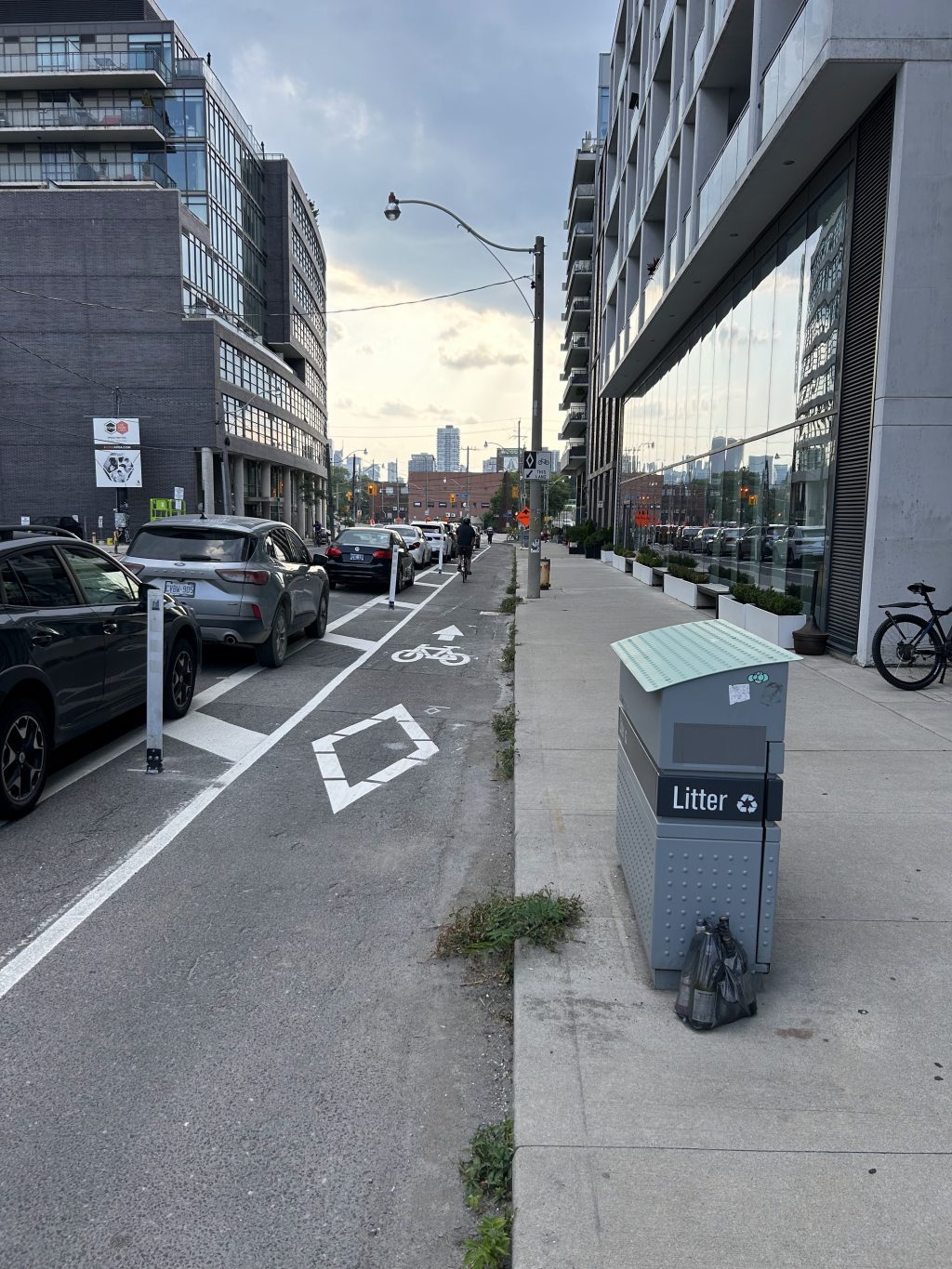 A person cycles in a cycle track that is located between a sidewalk and on-street parking
