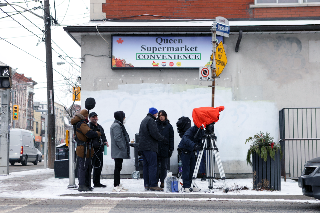 A film crew working outside of a corner store.